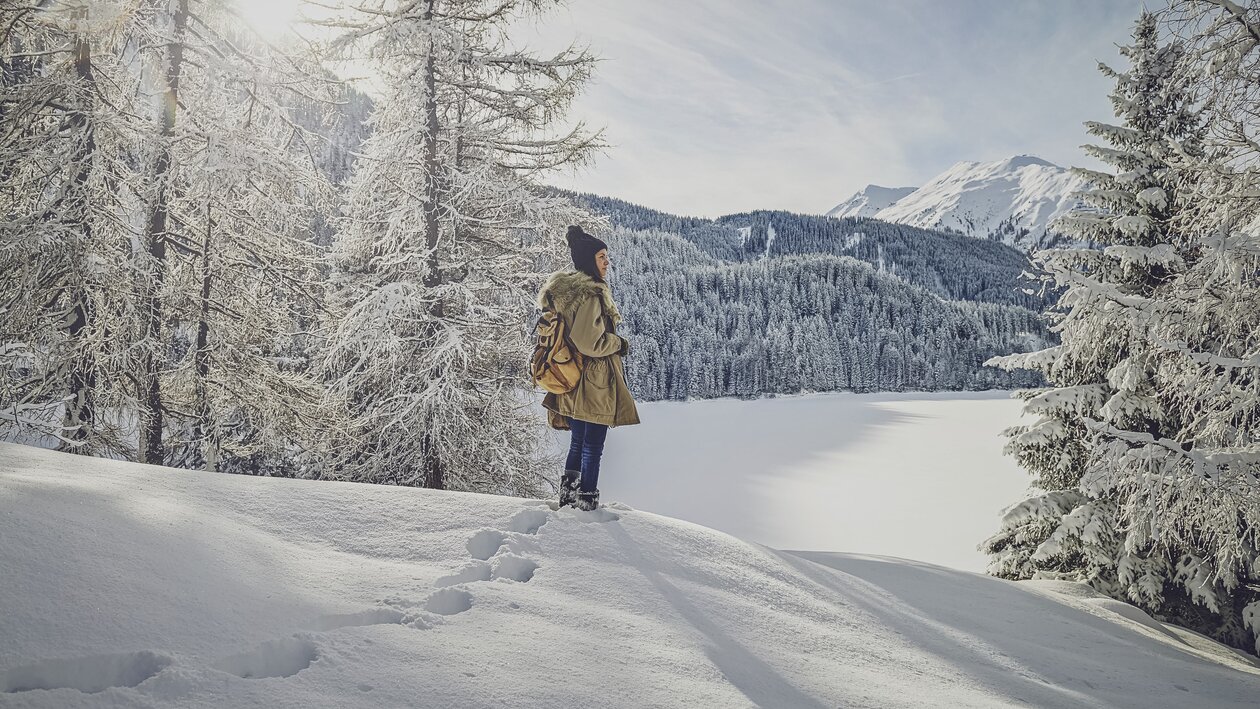 Feriengast vor dem verschneiten See in Davos im Winter. | © Davos Klosters Mountains