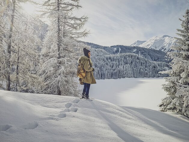 Tourist in front of the snow-covered lake in Davos in winter. | © Davos Klosters Mountains