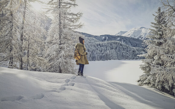 Feriengast vor dem verschneiten See in Davos im Winter. | © Davos Klosters Mountains