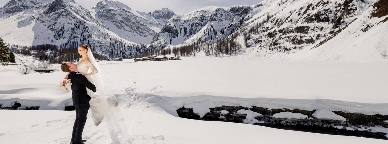 Glückliches Hochzeitspaar im Sertigtal Davos an einem herrlich sonnigen Wintertag | © The Tailors Photography | Julia Schneider-Reissle