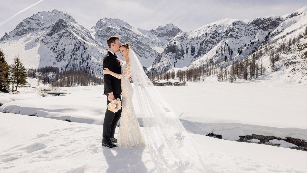Verliebtes Hochzeitspaar am Fluss im Sertigtal Davos im sonnigen Winter | © The Tailors Photography | Julia Schneider-Reissle