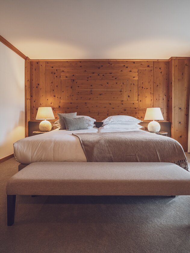 Doppelbettzimmer mit Bettwäsche, Nachttischlämpchen und Kleiderbank  | © Davos Klosters Mountains 
