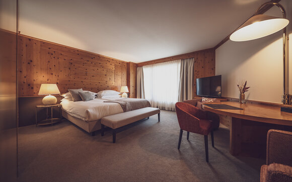 Grosses Hotelzimmer mit viel Holz, einem Doppelbett und einem Schreibtisch | © Davos Klosters Mountains