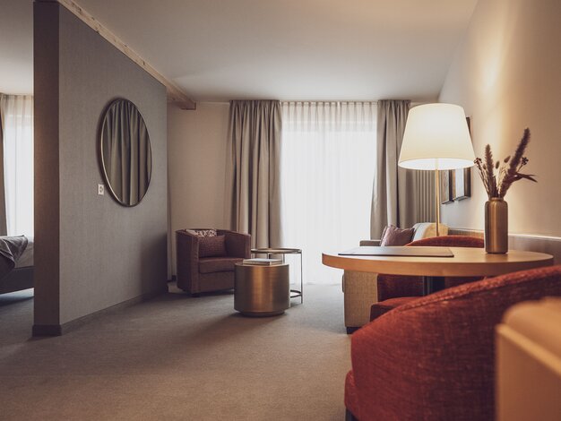 Hotelzimmer mit Salontisch, Vorhängen und Stehlampe  | © Davos Klosters Mountains 