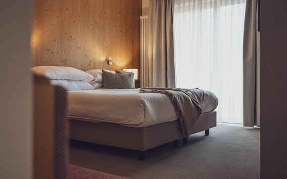 Doppelbett mit Bettwäsche und Vorhängen  | © Davos Klosters Mountains 